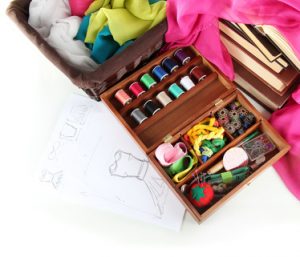 Sewing kit in wooden box with books and cloth isolated on white