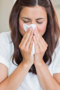 Sick woman with tissue on sofa